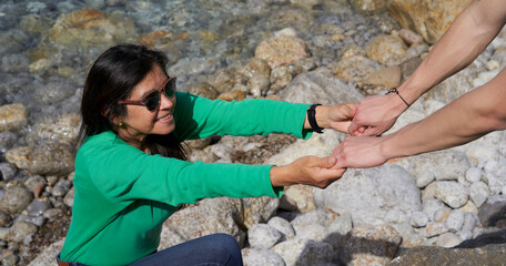 Fototapeta premium Man helping a woman to climb a mountain