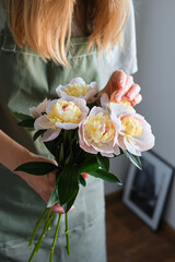 Peonies in the hands of a happy woman. Stylish white peonies in florist hand. The florist girl gathered a bouquet. Beautiful spring gentle flowers. Gift for the holiday. Fresh floral. Blossom petal