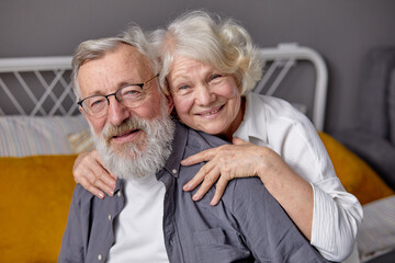 Portrait of cheerful senior couple relaxing at home in bedroom