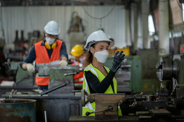 Factory woman worker with hygienic mask while working and checking production process at industrial plant.