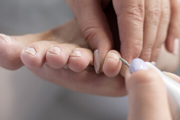 Pedicure. Close-up. Foot care procedure with a special electric device. Foot care for the client in the beauty salon. Space for text
