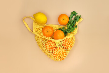 oranges and lemons with mint branches in a string bag