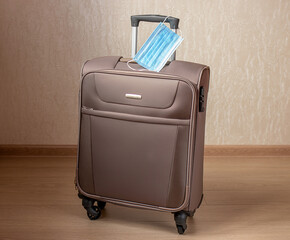 Suitcase for travel with a medical mask. Concept of travel during pandemic