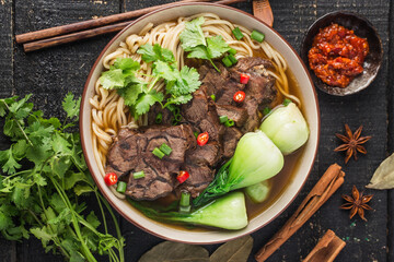 Spicy red soup beef noodle in a bowl on wooden table