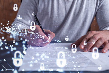 A businessman in casual wear signing the contract to prevent probability of risks in cyber security. Padlock Hologram icons over the working desk.