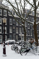 Fototapeta na wymiar Bicycles parked at the house on a snowy street. Amsterdam, Netherlands.