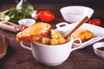 Cheese or onion cream soup with toasts bread in a white bowl