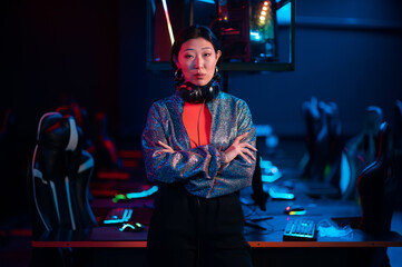 Young asian gamer in a headset poses for the camera with her arms folded