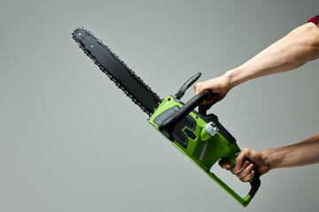Professional green chainsaw isolated on gray background