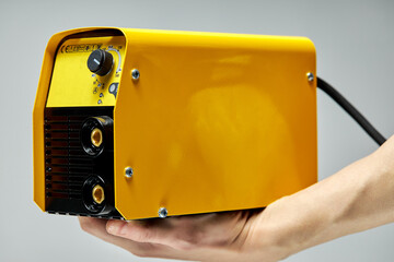 Fototapeta welding inverter machine, yellow colors,in hands of cropped male obraz