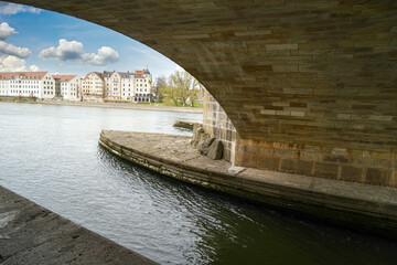 Stone bridge in Regensburg over the Danube with cathedral and Bruck Mandl