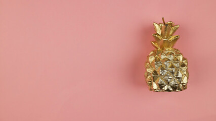Decorative shiny golden pineapple on a pink background. Gold pineapple on pink background trending color 2021-2022.