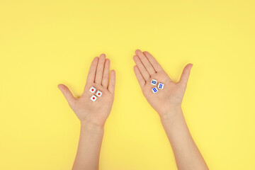 hands with dice on a yellow background