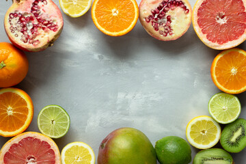 Colorful tropical, juicy citrus fruits in a circle on gray background; directly above