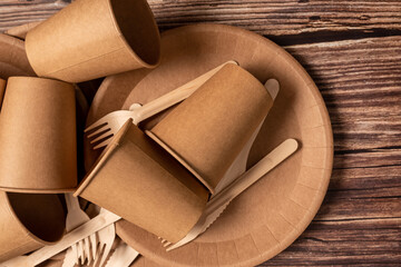The craft package contains disposable tableware, forks, knives and glasses. On a wooden background.