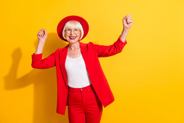 Photo portrait of senior woman wearing red suit hat glasses dancing laughing isolated bright yellow...