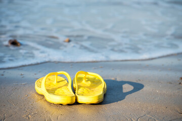 Fototapeta na wymiar Yelllow flip flops or sandals on beach. Holiday