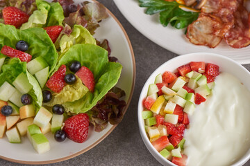 variety of open sandwiches made of brown whole wheat  bread with tomatoes sauce, bowl of oat granola with yogurt, white beans, bacon, fried egg. fresh fruit and vegetable salad, healthy breakfast.