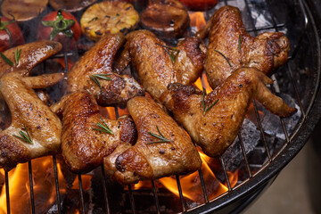 Grilled chicken wings on the flaming grill with Grilled vegetables in barbecue sauce with pepper seeds rosemary, salt. top view with copy space. tasty snack. Flat lay. Healthy lunch menu. Diet food.