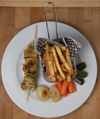 Lamb skewer with sesame seeds, served with fries, carrot, zucchini and white onions