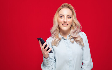 Naklejka premium Happy woman with phone, isolated on red background. Trendy happy girl using mobile phone
