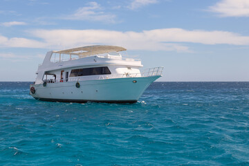 White motor boat against the background of the blue sea and blue sky with clouds, walks in the Red Sea, diving and snorkeling in the open sea
