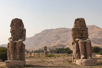 Fototapeta na wymiar Colossi of Memnon - the ancient guardians of the temple of Amenhotep III at the entrance to the nonexistent ruined burial temple, the city of the dead Luxor