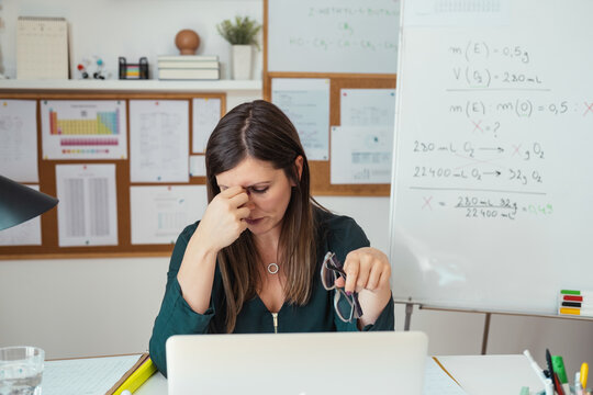 Young Tired Female Professor Having Headache.
Teacher Holding Online Class For E-learning Students At Home During COVID-19 Pandemic Period. Stressed Woman Take Off Glasses Feel Pain Rub Closed Eyes