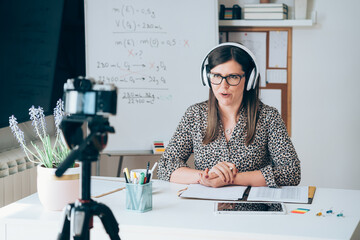 Teacher recording video tutorial for e-learning class. Female professor working from home teaching...