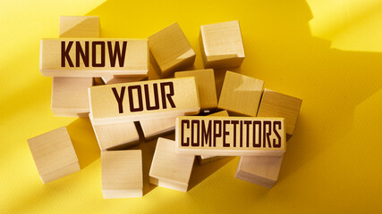 The text KNOW YOUR COMPETITORS is written on wooden blocks and on a yellow background.
