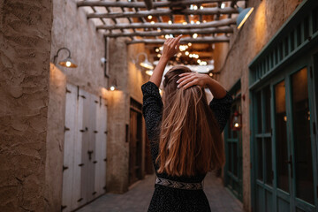 Happy woman traveler wearing black dress walking through the streets