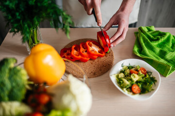 male hands chopping salad and onion, cooking healthy food in the kitchen.