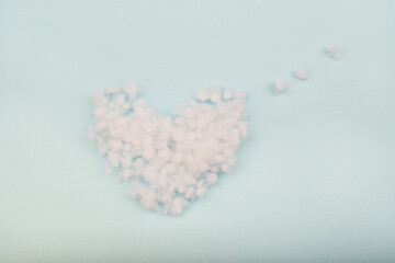 The filler is sintepon. Type Pillow Material. White synthetic sintepon filler in the form of a heart on a blue background, soft texture.