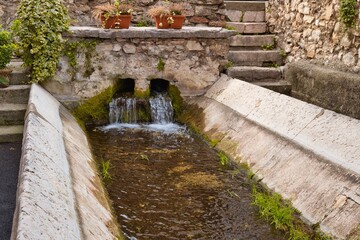 Fototapeta na wymiar Fontana e roggia con scale in pietra nel comune di Isera in trentino