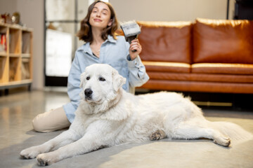 Woman combs the dog's hair with a brush