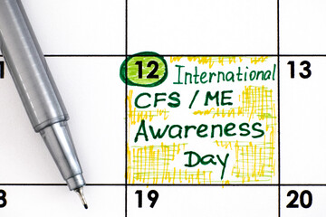 Reminder International CFS/ ME Awareness Day in calendar with pen.