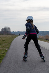 inline skates draußen, ein Mädchen im weißen Helm Rückenansicht. Sport draußen.