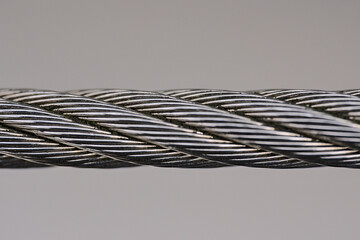 Beautiful isolated macro view of steel wire rope on solid gray background. Metal rope fence, edging...