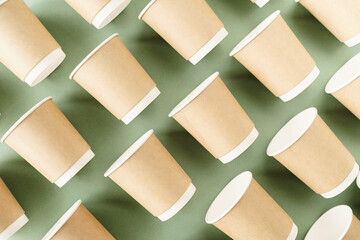 Disposable paper cups pattern top view on green background