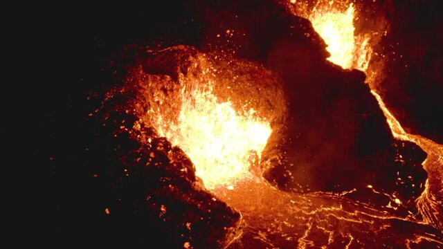 Incredible night time aerial drone view of lava spewing from an active erupting volcano.