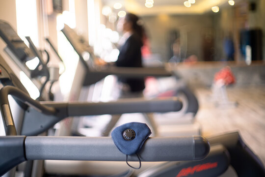 Shallow depth of field shot with a face mask to prevent infections like COVID 19 pandemic from spreading on a treadmill as people excercise to build immunity and recover 