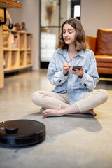 Relaxed woman with phone and robotic vacuum cleaner