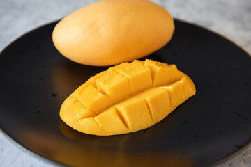Fresh yellow mango fruit in a black plate