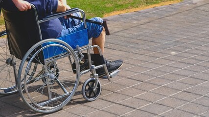 Fototapeta na wymiar Elderly man with diabetes and kidney disease sitting on wheelchair walking with assistant in the park.