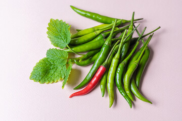 Slide of green chili peppers with one red on a light background.