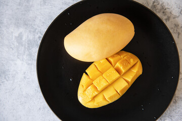 Fresh yellow mango fruit in a black plate
