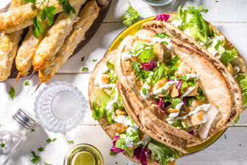 Mediterranean food. Doner Kebap, Taco, Shawarma, greek wrapped gyros sandwich, tortilla pita bread stuffed grilled chicken meat, fresh vegetables, tsatziki sauce. Sunny white wooden table copy space