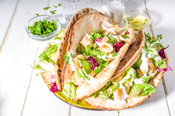 Mediterranean food. Doner Kebap, Taco, Shawarma, greek wrapped gyros sandwich, tortilla pita bread stuffed grilled chicken meat, fresh vegetables, tsatziki sauce. Sunny white wooden table copy space