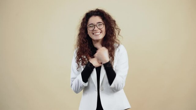 Cheerful young woman with curly hair, laughing out loud, leaning forward and pointing to the room.