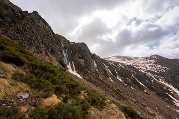 Estany de la Gola. On an early spring day. In the midst of the melting snow of winter, forming waterfalls on the tops of the mountains that end at the bottom of the valley.